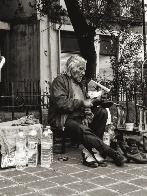 Foto dakloze man die op een voetpad in de stad zit