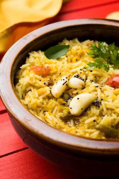 Dal khichadi or Khichdi Tasty Indian recipe served in bowl over moody background is made of toovar dal and rice combined with whole spices, onions, garlic and tomatoes etc. Selective focus