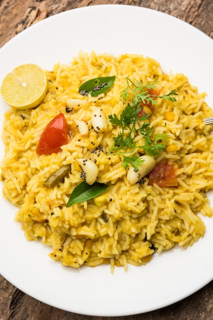 Dal khichadi or Khichdi Tasty Indian recipe served in bowl over moody background is made of toovar dal and rice combined with whole spices, onions, garlic and tomatoes etc. Selective focus