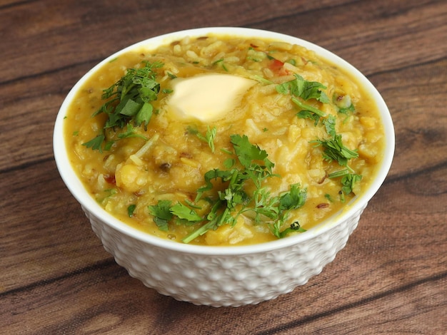 写真 dal khichdi または khichadi おいしいインドのレシピは、素朴な木製の背景の上にボウルで提供されます.dal と米で作られた食べ物は、全体のスパイス、タマネギ、ニンニク、トマトなどを組み合わせたものです.選択と集中