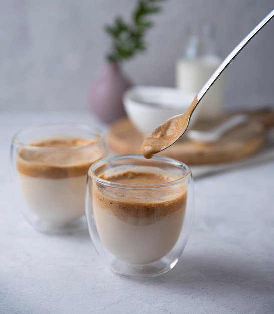 Dalgona coffee in glasses with vegan milk on light background