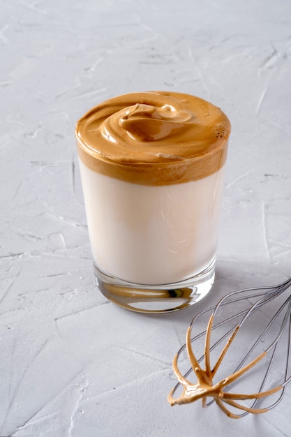 Photo dalgona coffee. milk topped with whipped instant coffee