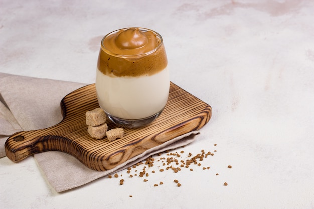 Dalgona Coffee in a transparent cup on desk.