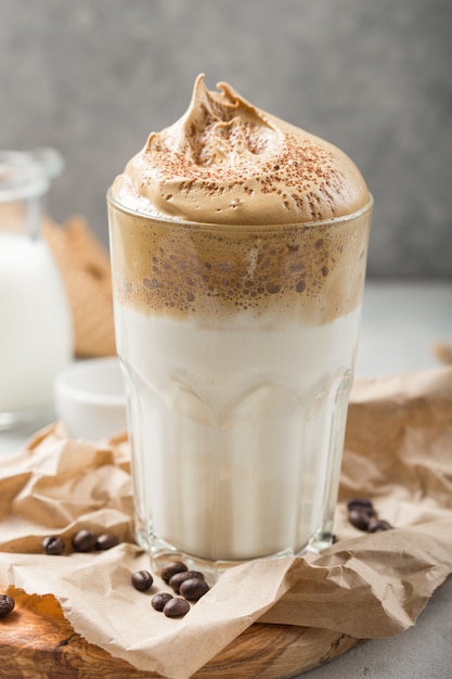 Dalgona creamy coffee in a glass on a light gray background with whipped foam. Korean food trend, Vertical format