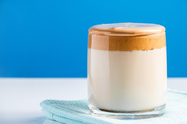 Dalgona-koffie op een blauwe achtergrond Modieuze trenddrank van melk en zoete slagroom