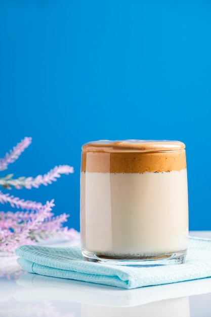 Dalgona-koffie op een blauwe achtergrond Modieuze trenddrank van melk en zoete slagroom