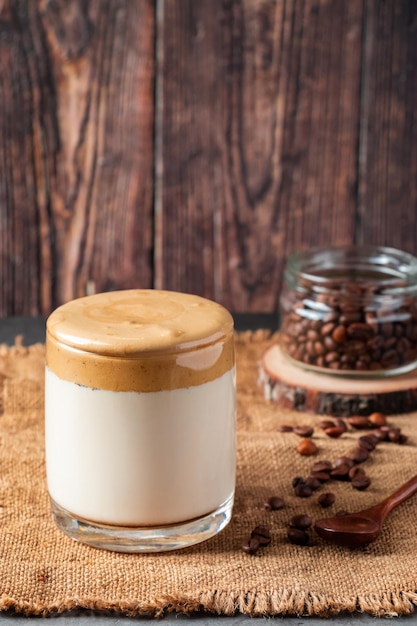 Dalgona-koffie op een houten ondergrond Een glas trendy drank gemaakt van melk