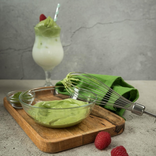 Dalgona matcha cream  in a bowl whisk   green napkin  on a grey background  Trendy drink