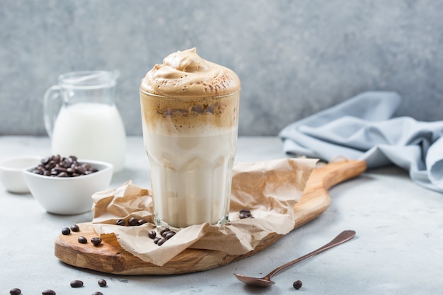 Dalgona schuimende koffie in glas op grijs. Trend koreaanse latte met schuim van instant koffie. Detailopname.