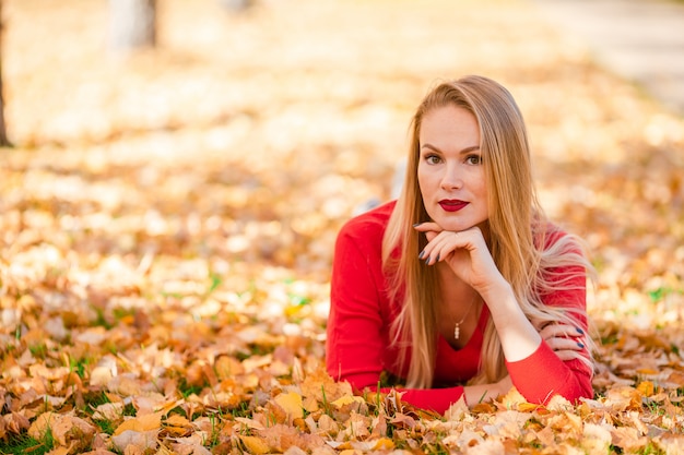 Dalingsconcept - mooie vrouw het drinken koffie in de herfstpark onder dalingsgebladerte