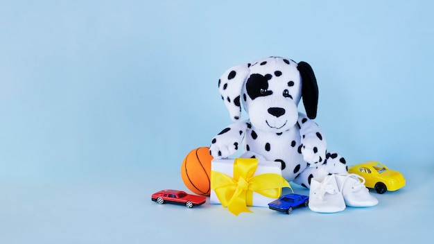 Photo dalmatian puppy toy with small present toy cars and basketball ball on light blue background