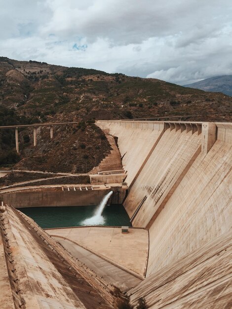 Photo dam by mountain against cloudy sky