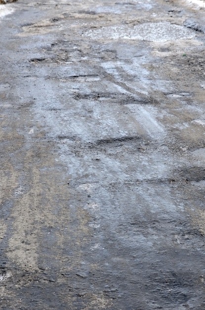 Strada asfaltata danneggiata con buche causate da cicli di congelamento e scongelamento durante l'inverno. strada povera