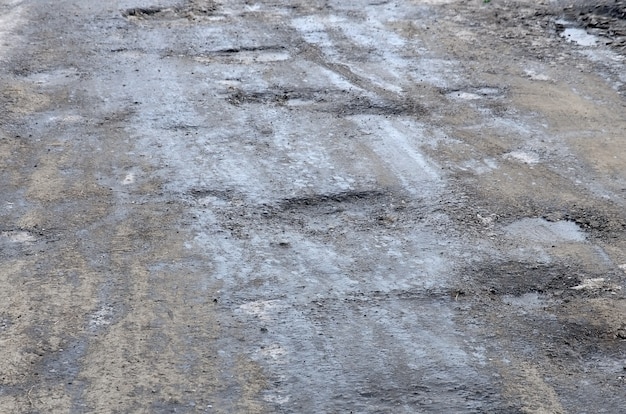 Strada asfaltata danneggiata con buche causate da cicli di congelamento e scongelamento durante l'inverno