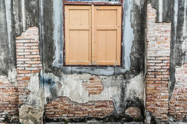 Foto parete di mattoni danneggiata e finestra chiusa