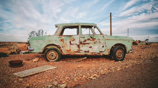 Damaged car on field against sky