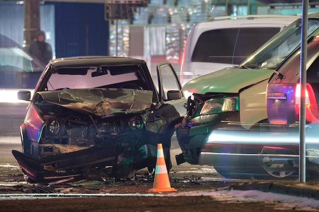 Damaged in heavy car accident vehicles after collision on city street crash site at night Road safety and insurance concept