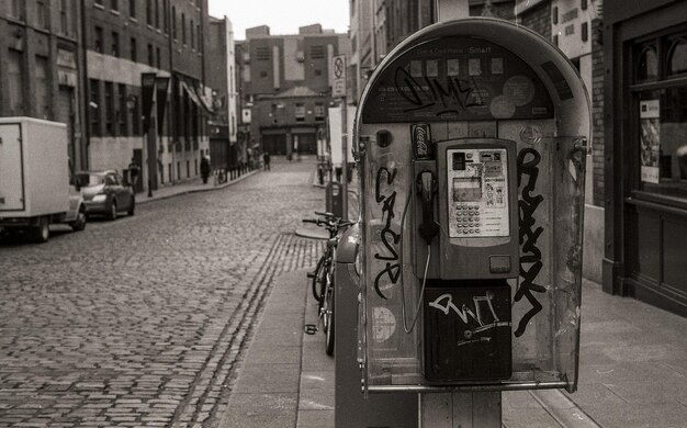 Photo damaged pay phone on sidewalk in city