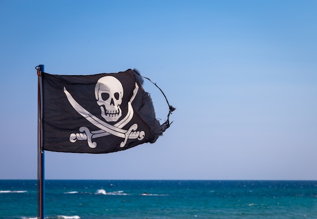 A damaged pirate flag during a strong windy day, with copyspace