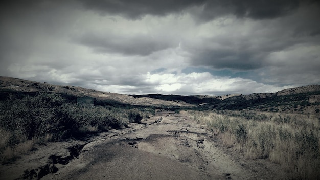 写真 雲の空に逆らって山へ向かう破損した道路