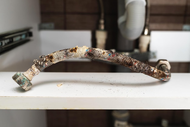 Damaged water hose with traces of corrosion deformation of the protective layer and limescale