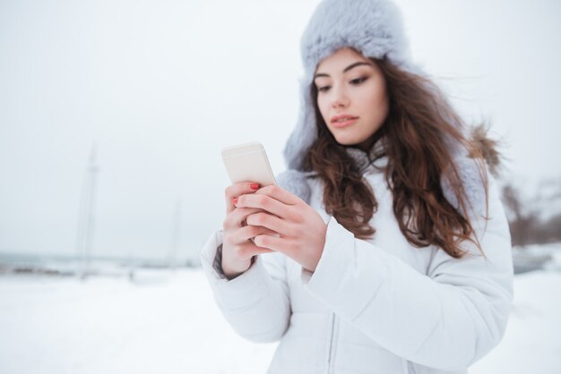 Dame die hoed draagt die door haar telefoon babbelt.