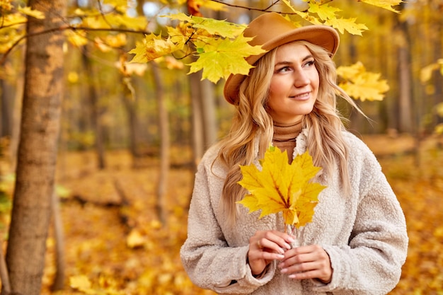 Dame geniet ervan om in de herfstbos, natuur te zijn. mooie blanke blonde vrouw in hoed