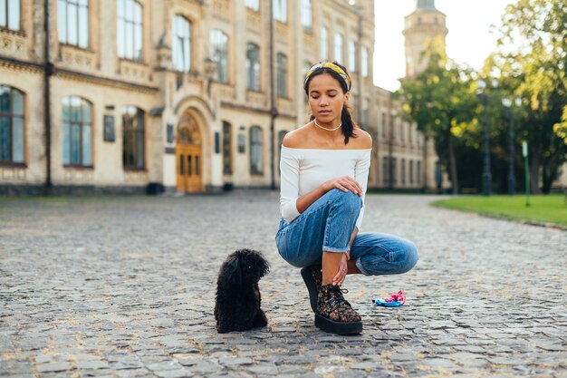 Dame zit op straat met een kleine hondenras speelgoedpoedel en kijkt naar het huisdier