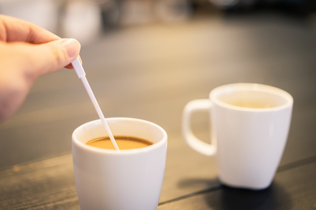 Damehand die koffielepel houden en hete koffie bewegen