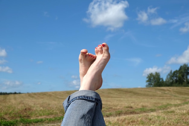 Dames blote voeten met rode nagels tenen tegen zomer landschap closeup