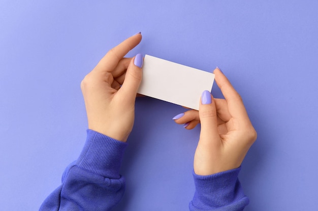 Dames hand met visitekaartje op paarse achtergrond zakelijke werksjabloon mockup