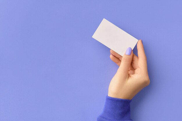 Dames hand met visitekaartje op paarse achtergrond zakelijke werksjabloon mockup