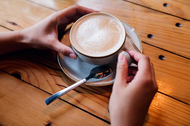 Dames handen met een kopje koffie op een tafel