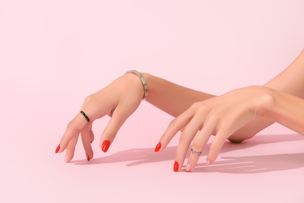 Dames handen met rode manicure op roze achtergrond manicure design trends