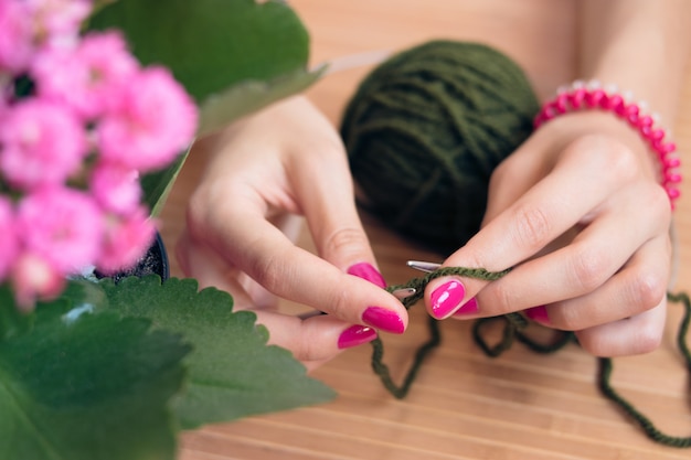 Dames handen met roze manicure gebreide metalen spaken