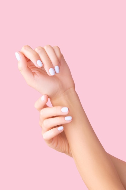 Dames handen met witte manicure op roze achtergrond