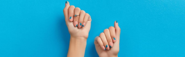 Dames handen met zomer manicure op blauwe achtergrond