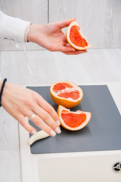 Dames handen snijden verse grapefruit op keuken