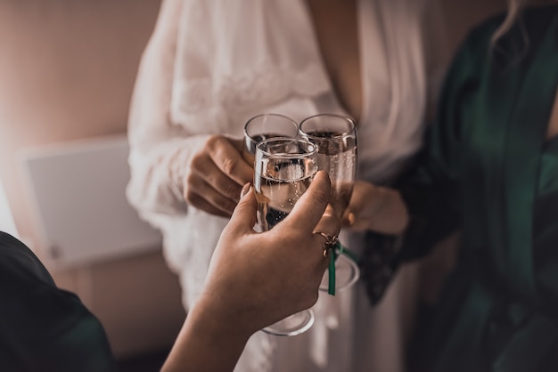 Dames in witte en zijden gewaden klinken glazen champagne