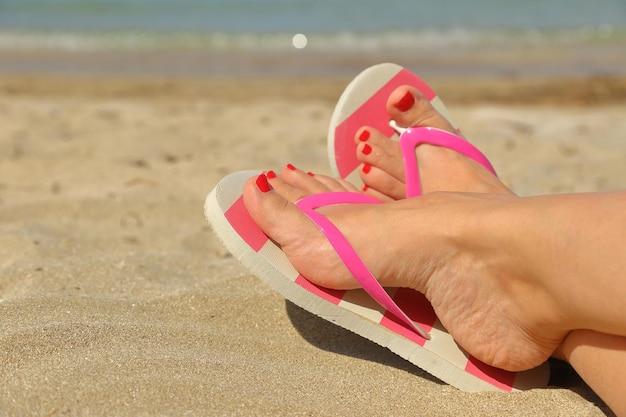 Dames voeten met slippers op het zand