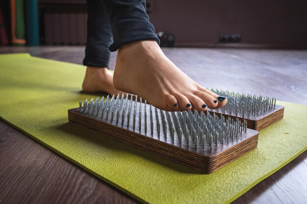 Foto damesbeenstappen op sadhu-bord met spijkers voor concept met yogamassagethema