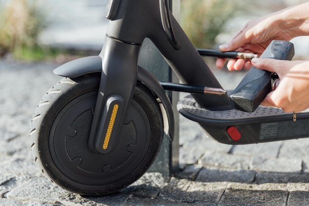 Dameshanden houden de fiets vast, zodat de elektrische scooter niet wordt gestolen, laat hem veilig beschermd