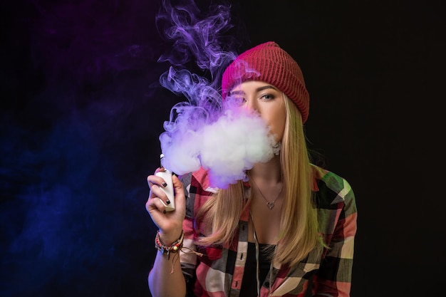 Dampend meisje. Jonge hipster vrouw vape e-sigaret op studio op zwarte achtergrond. Hiphop-stijl. Detailopname.