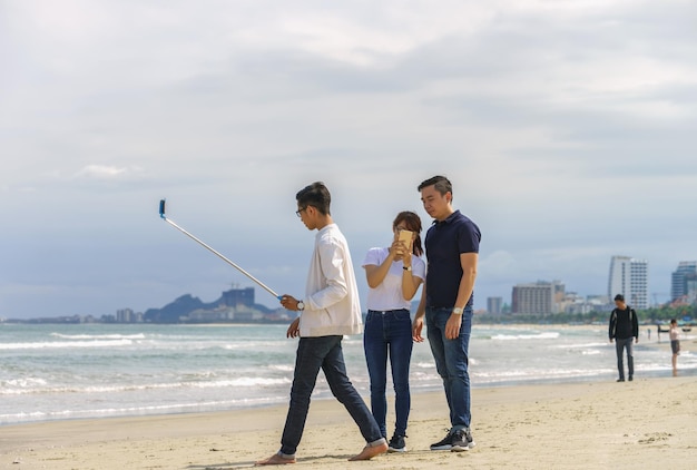 Danang, Vietnam - February 20, 2016: Young people use a selfie stick at the China Beach on Danang in Vietnam