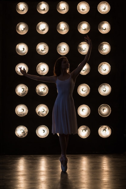 Foto danza ballerino di balletto sta ballando nella sala buia con lampade ballerina di giovani donne che si esercita