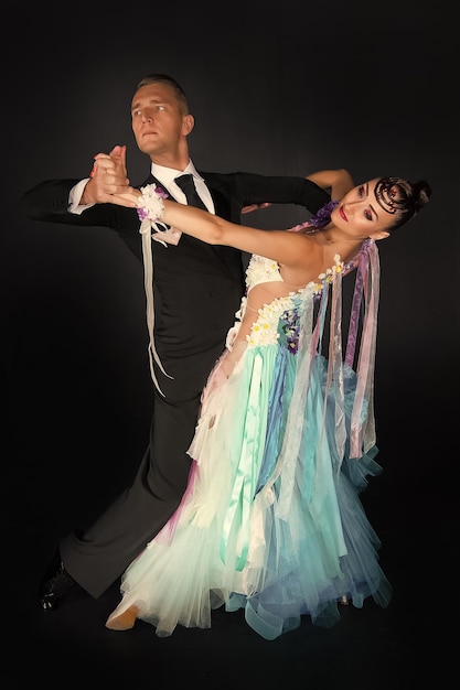 화려한 드레스 댄스를 입은 댄스 볼룸 커플은 검정색 배경에 격리된 관능적인 전문 댄서 왈츠 탱고 슬로우폭스와 퀵스텝을 추고 있습니다.