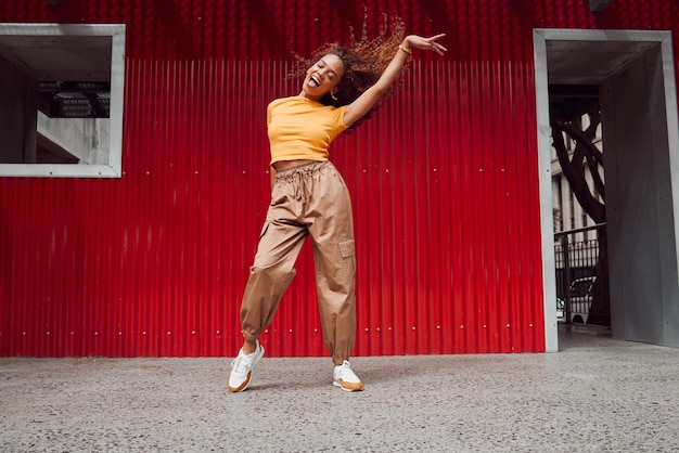 Dance freedom and fun with a black woman on a red background dancing or happy with a smile while moving to music Dancer free and expression with an attractive young female in rhythmic movement