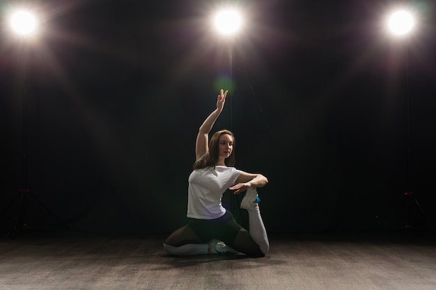 Dance, hip-hop, jazz funk and people concept - flexible young woman dancing in the darkness under the light.