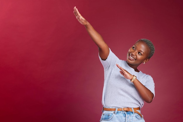 Dance marketing and happy black woman in studio with a red background in celebration of a sale or discount Success winner and excited African girl dancing with pride with advertising mockup space