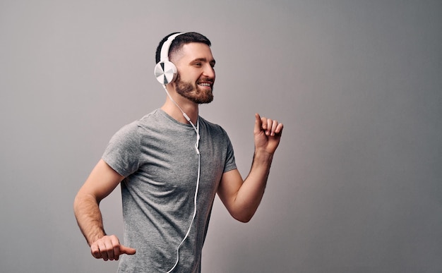 Dance to your favorite song in your favorite headphonesBeautiful young man dancing on a gray wall